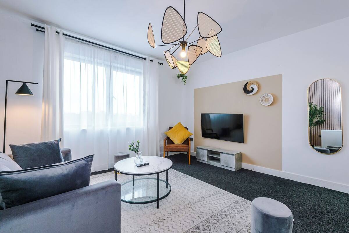 Un salon moderne comprenant un canapé, une table basse, un téléviseur et des objets de décoration.