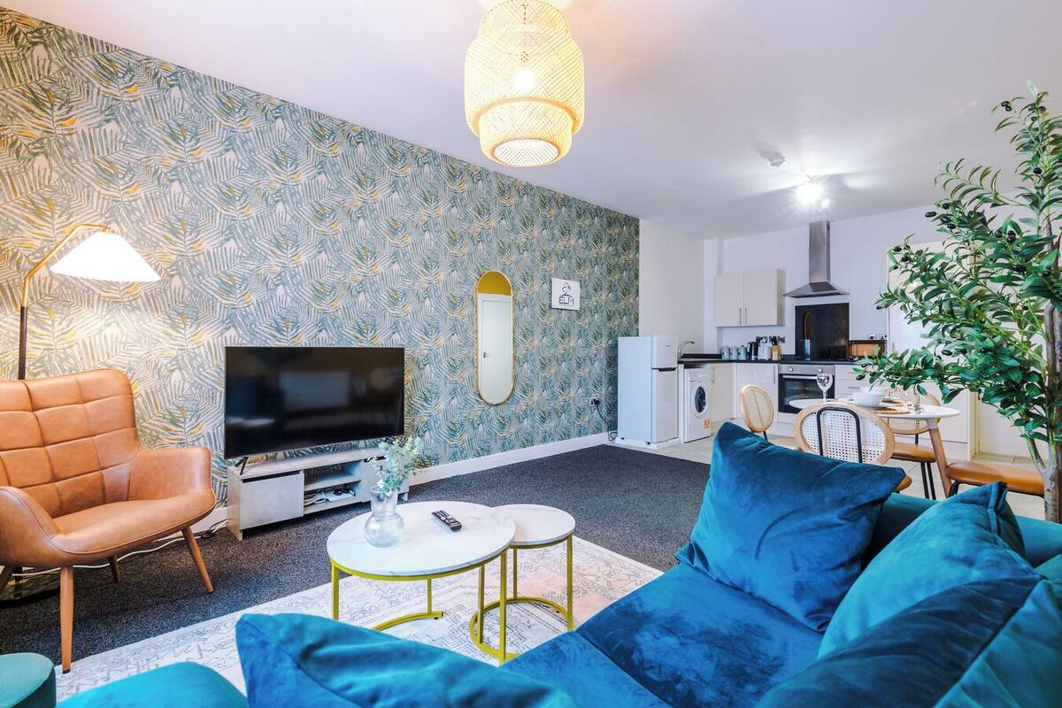 Un salon moderne comprenant un canapé, un téléviseur et un coin repas avec une table et des chaises.