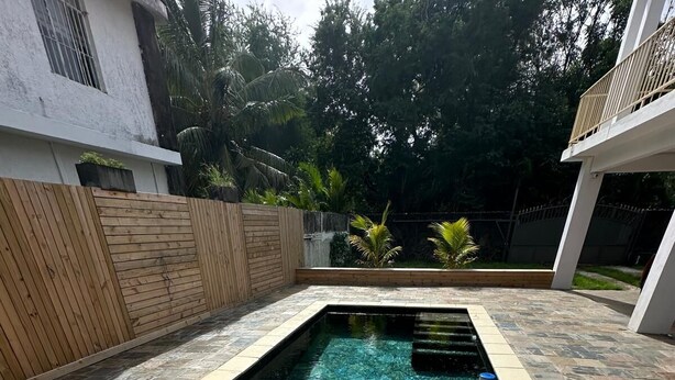 Une piscine rectangulaire dont le bord est recouvert de carreaux, entourée d’une terrasse en pierre.