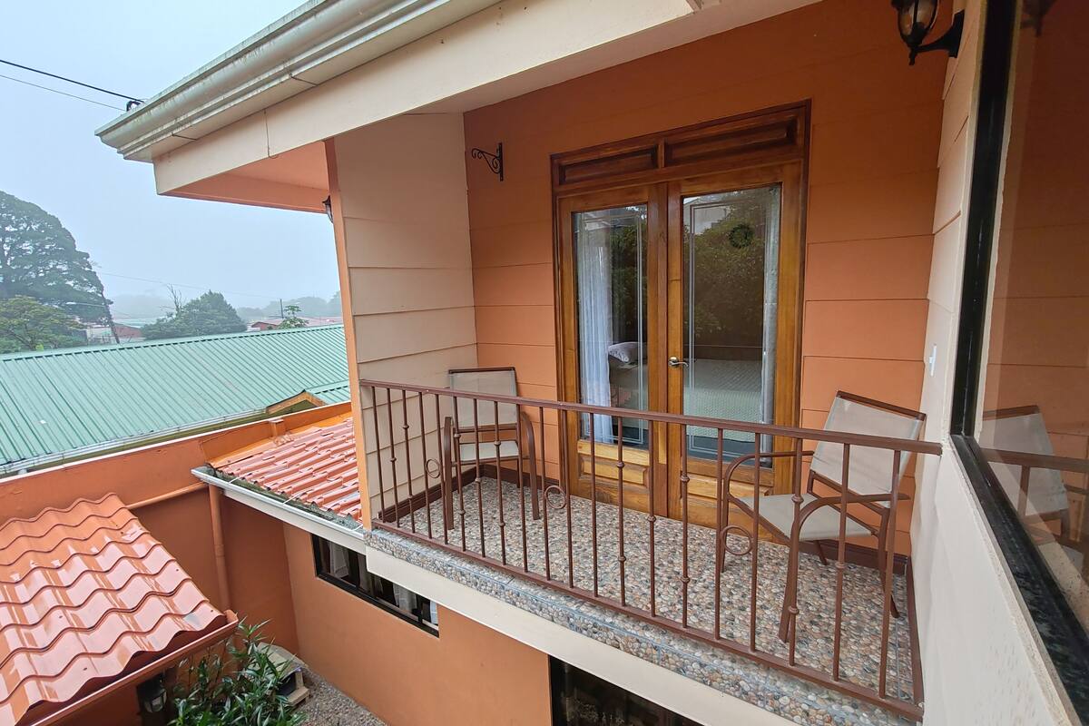 A balcony with a glass door, a small table, and a chair.