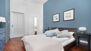 Un dormitorio con cama, mesitas de noche, un armario y una puerta.
