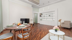 Un comedor moderno con una mesa redonda de madera, sillas con cojines a rayas y una mesa de centro blanca con un arreglo floral.
