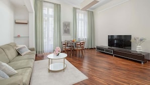 Una sala de estar moderna con un sofá, una mesa de comedor, sillas, un televisor y piso de madera.