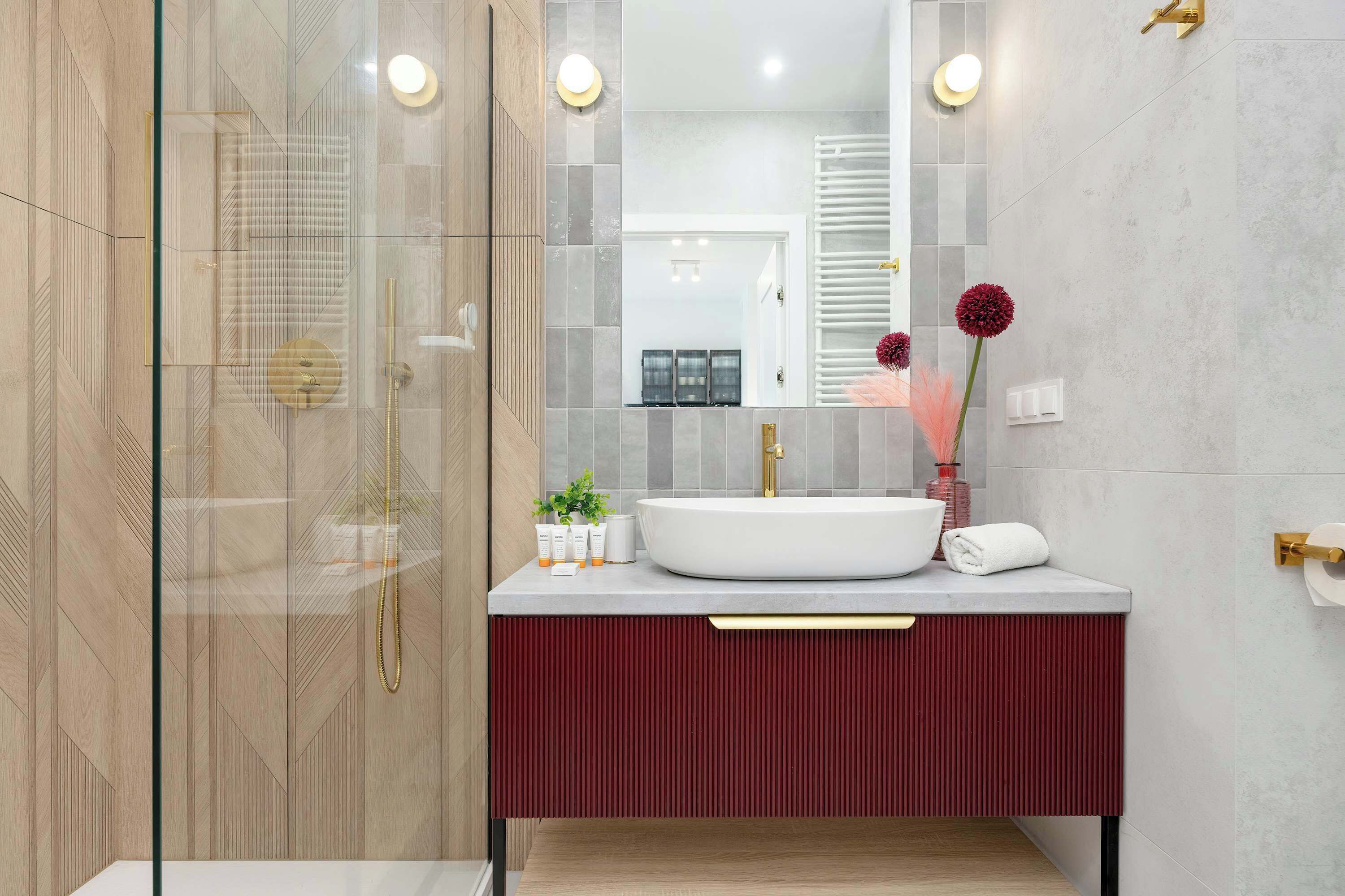 A modern bathroom with a glass-enclosed shower, a white sink, and a red vanity.