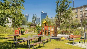 Um parque com brinquedos, mesas para piquenique e bancos.