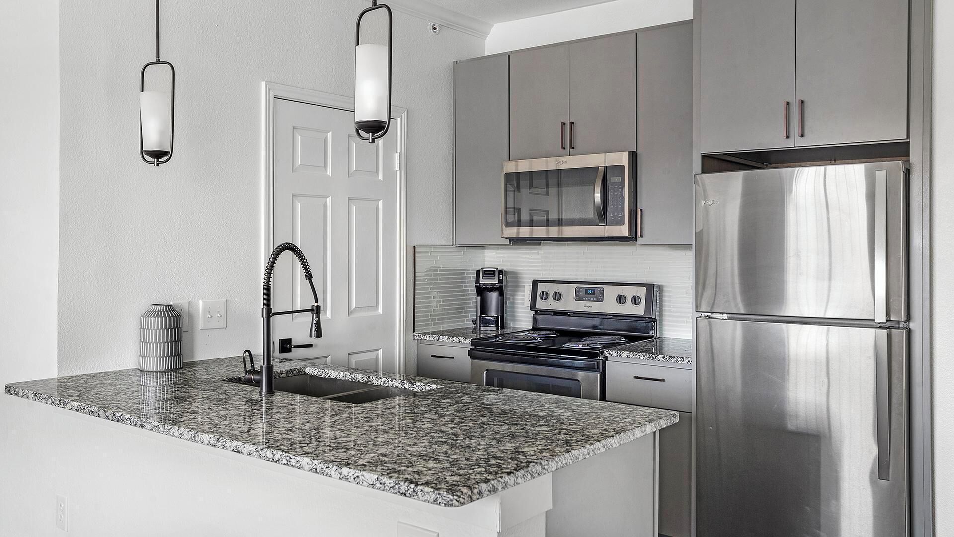 A modern kitchen with granite countertops, stainless steel appliances, and a built-in oven.