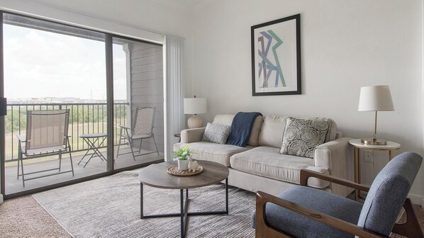 A living room with a sofa, armchairs, a coffee table, and a balcony with chairs. - Landing | Amazing 2BD, Pool, Clubhouse (Austin)
