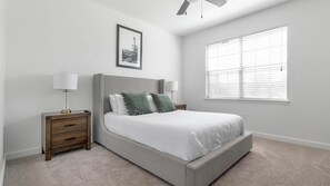A bedroom with a bed, two bedside tables, a ceiling fan, a window with blinds, and a framed picture on the wall. - Landing | Incredible 1BD, Gym, Pool (Austin)