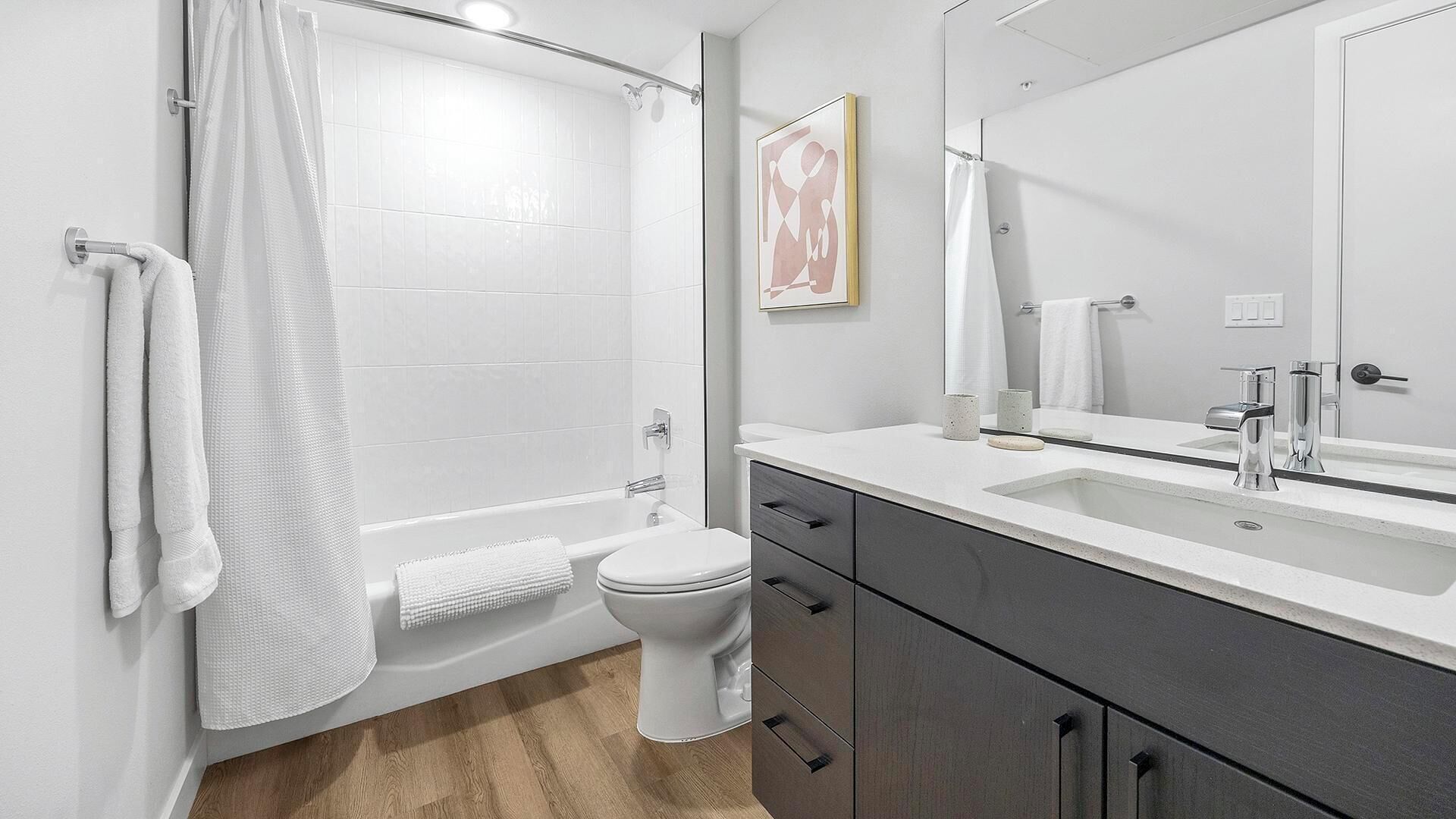 A modern bathroom with a shower, toilet, and vanity.