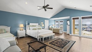 A bedroom with a large bed, a desk, a chair, a ceiling fan, and a view of the outside. - Large Pet Friendly Gulf Front House with Pool and Elevator! (Gulf Shores)