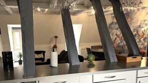 A modern kitchen with white cabinets, a wooden countertop, and a decorative wall mural. - Charming apartment with character (Nevers)