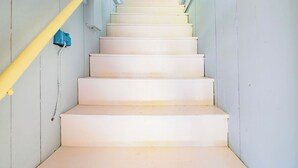 A staircase with white steps and a yellow handrail, leading to a door at the top. - Sweet Thing Summary: (Portland)