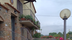 Un edificio in pietra con un balcone, una scala e piante in vaso.