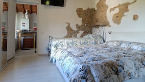 Una camera da letto con un letto grande, una TV a parete e un muro in pietra rustica.