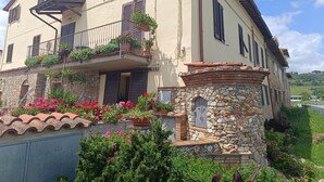 Un edificio di due piani con un balcone, facciata in pietra e piante in vaso.