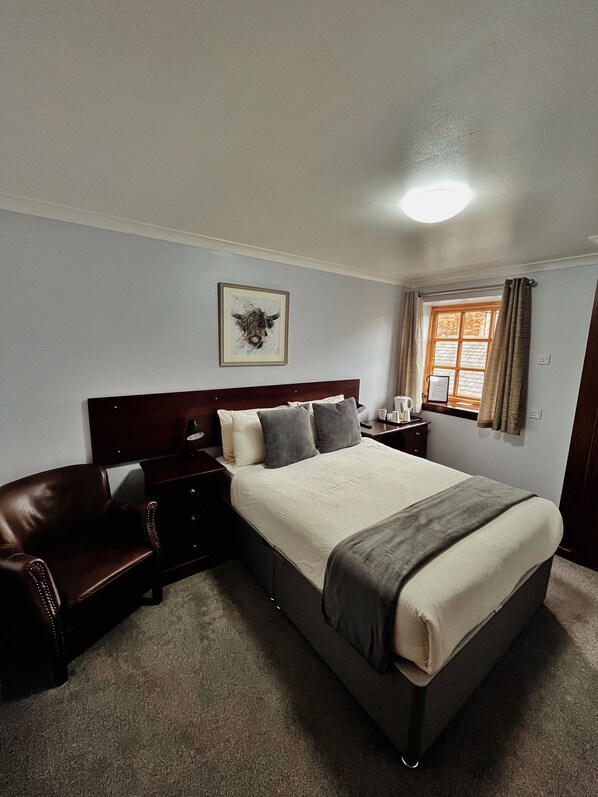Une chambre à coucher avec un grand lit, une tête de lit en bois, un canapé en cuir marron, une table de chevet avec une lampe et un tableau encadré au mur.