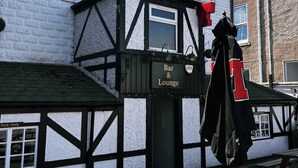 The Stag Hotel, con insegna Bar & Lounge, facciata in legno e tavoli da picnic all'esterno.