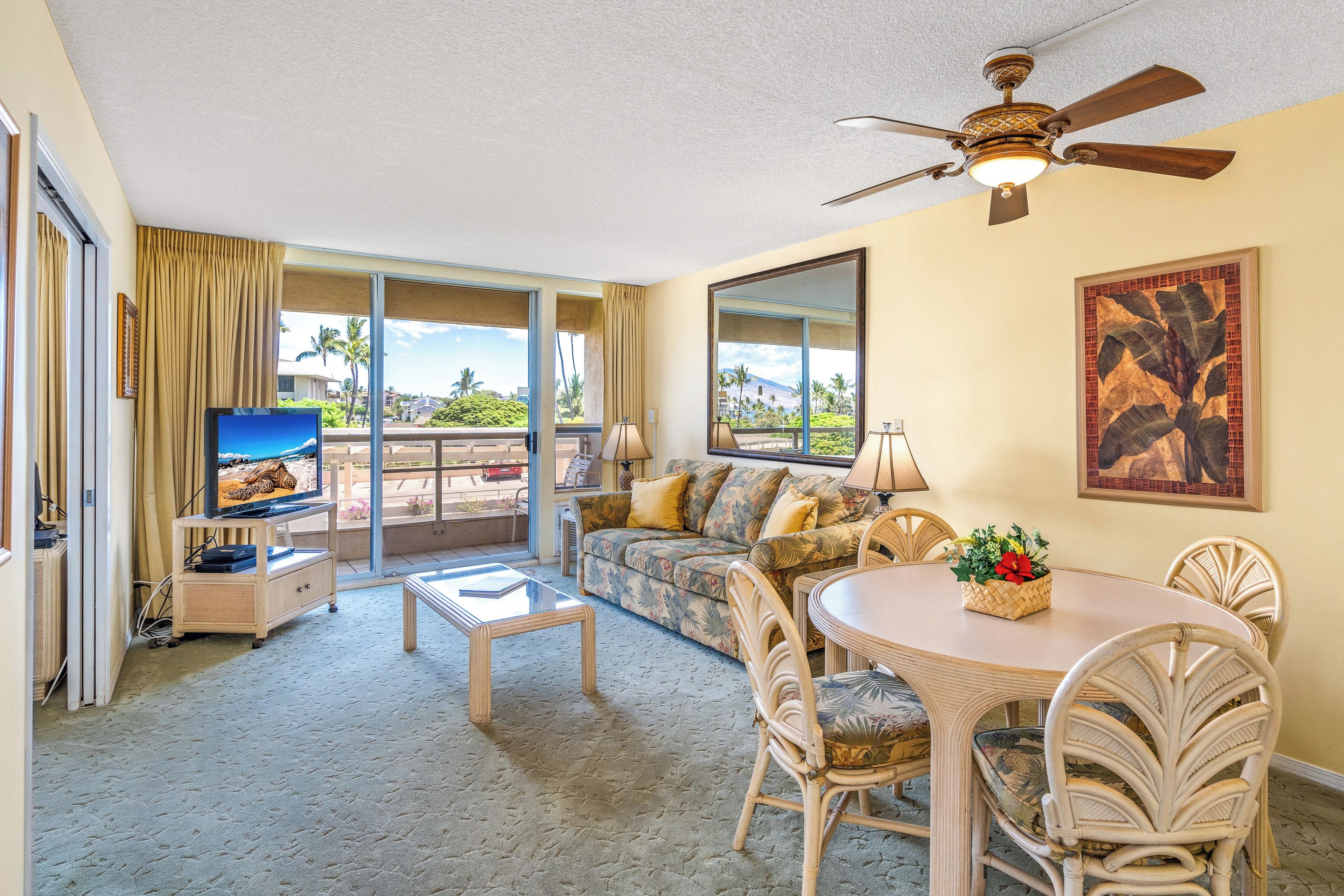 A spacious living room with a television, a sofa, a dining table, and chairs.