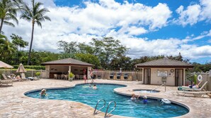 A swimming pool with multiple sections, lounge chairs, and a covered seating area.