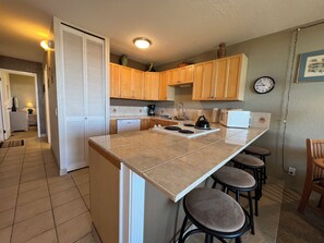 A kitchen with wooden cabinets, a white stove, and a bar stool.