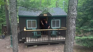 Una baita con veranda, circondata da alberi.