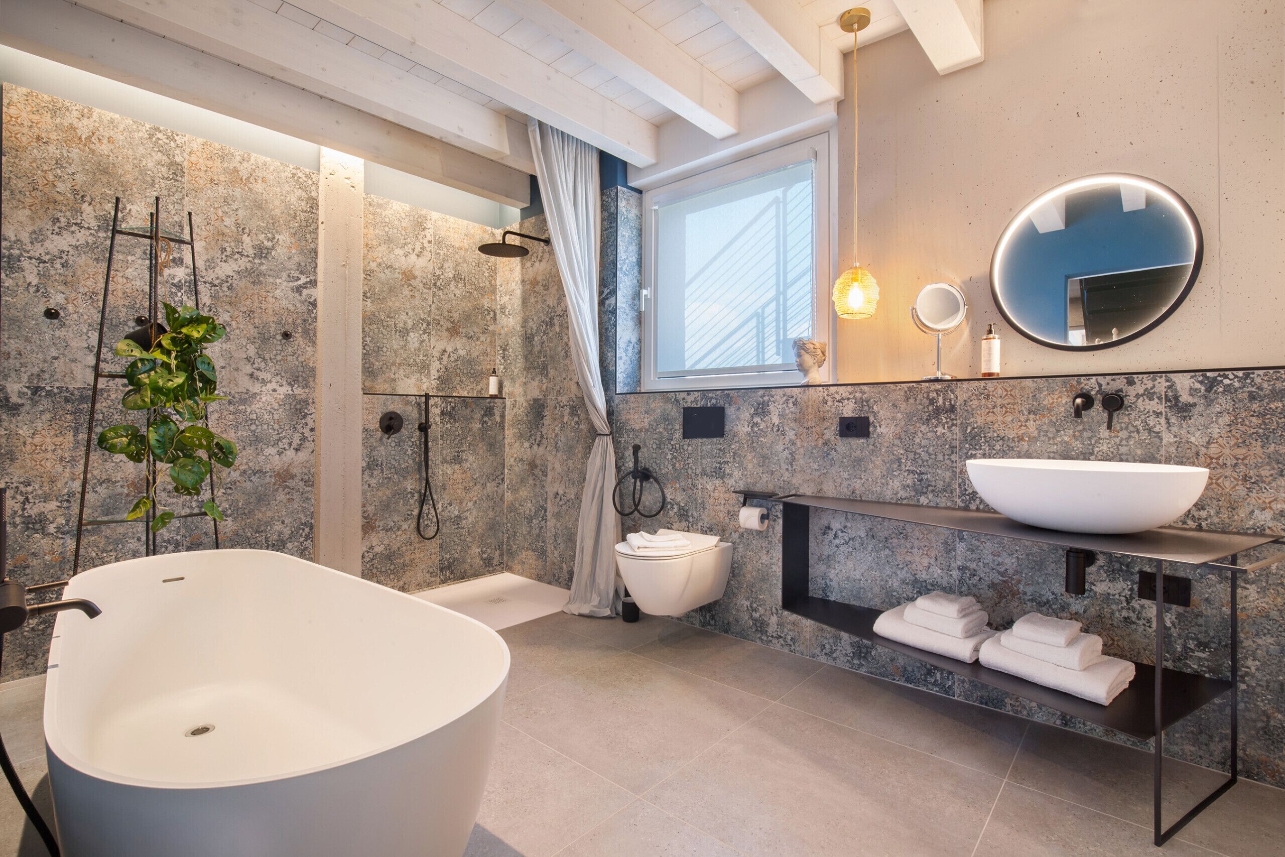 Ein modernes Badezimmer mit einer freistehenden Badewanne, einem großen Spiegel und einem integrierten Waschtisch mit einer Aufsatzwaschbecken.