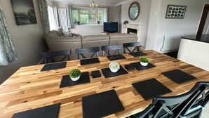 A modern living room with a wooden dining table, black chairs, and a grey sofa.