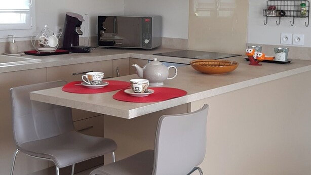 Eine moderne Küche mit einer zentralen Kochinsel, zwei Barhocker, einer Mikrowelle und einer Kaffeemaschine.