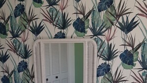 Ein Zimmer mit einem Bett, einem weißen Schminktisch, einem Spiegel und einem blauen Sessel.