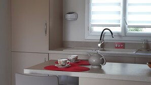 Eine moderne Küche mit integrierter Kochinsel, einem Fenster mit Jalousien und einem Stuhl aus Edelstahl.