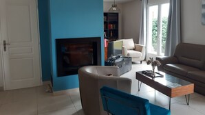 Ein Wohnzimmer mit blauer Akzentwand, Kamin, einer Couch, einem Couchtisch und einem Bücherregal.
