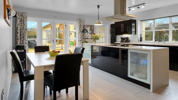 A modern kitchen with a central island, black cabinets, and a dining area with a table and chairs.