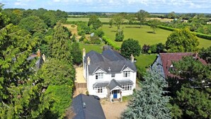 A large house with a well-maintained lawn and surrounding trees.
