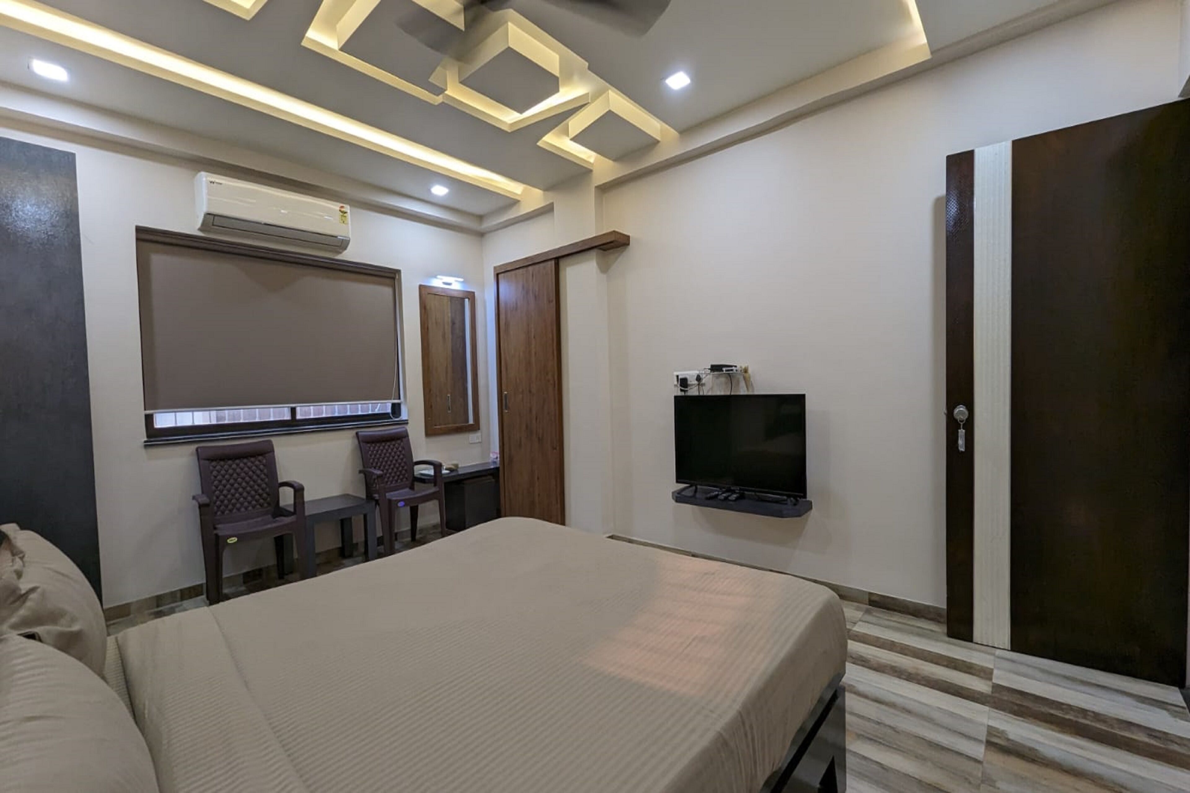 Habitación de hotel con cama, escritorio, silla, televisor y armario.