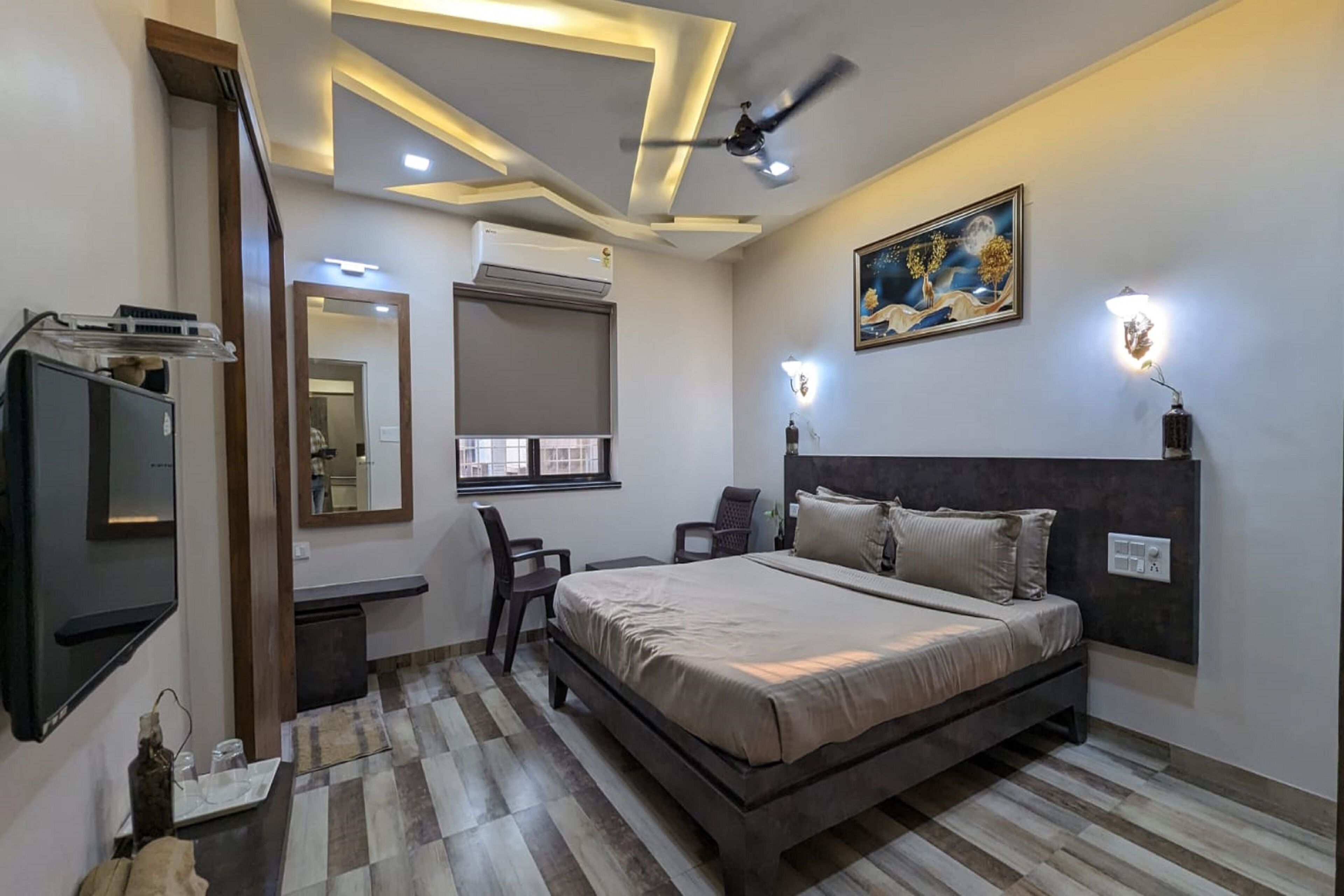 Quarto moderno com uma cama grande, uma escrivaninha, uma cadeira, uma televisão e um ventilador de teto.