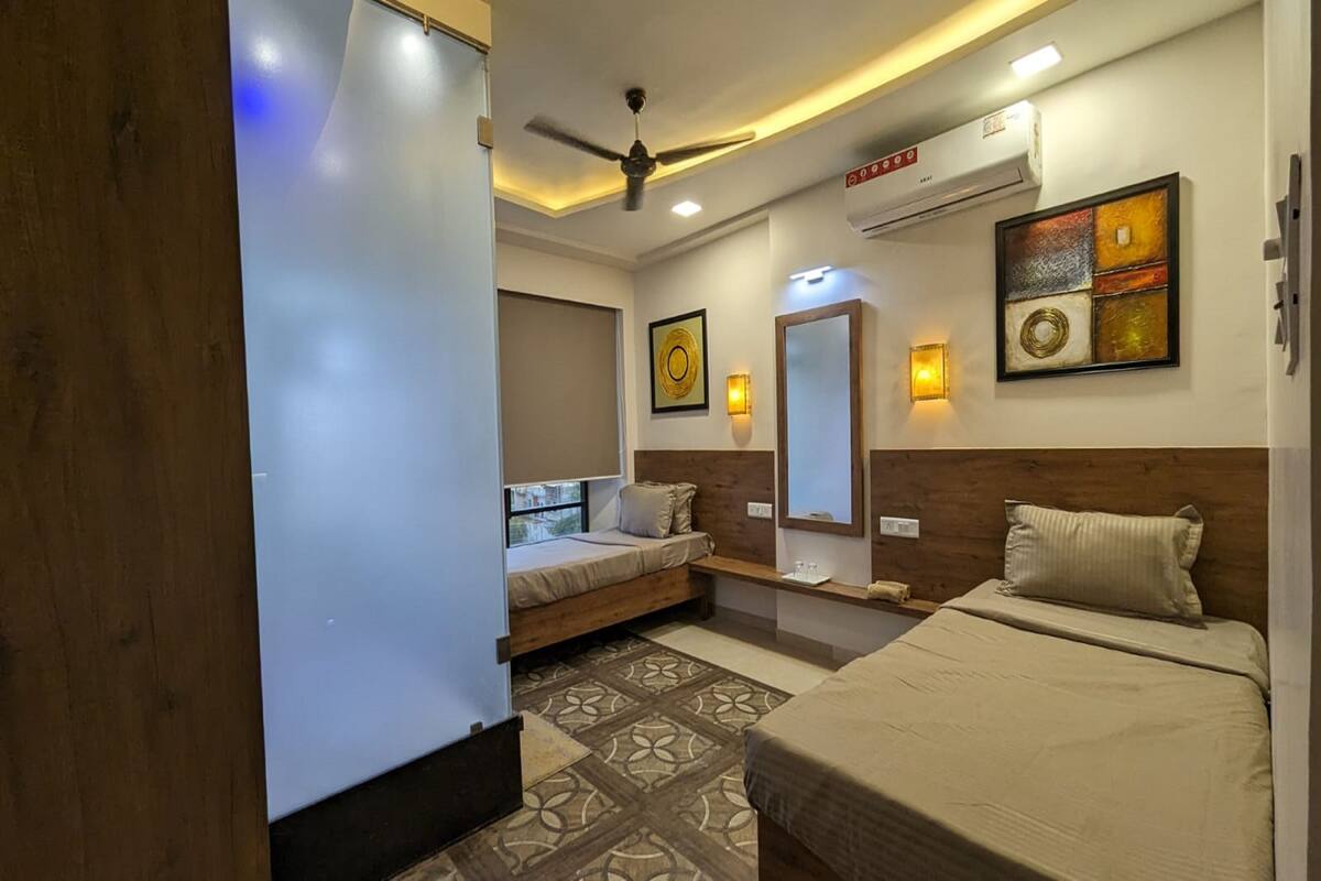 A modern hotel room with a bed, a sofa bed, a ceiling fan, and a wall-mounted air conditioner.