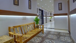 A hallway with a wooden bench, a potted plant, and framed artwork on the walls.