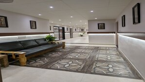 A hallway with a black leather sofa, a wooden bench, and a patterned rug.