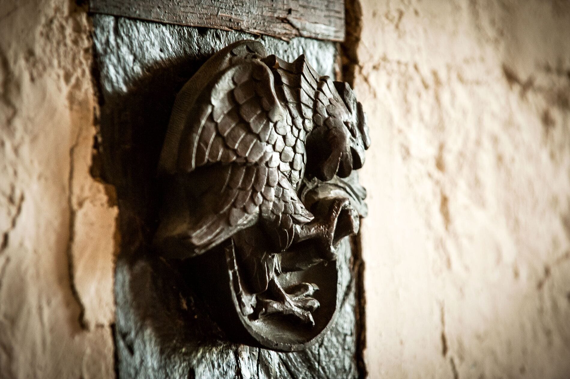 A detailed metal sculpture of a bird, possibly an eagle, mounted on a textured wall.