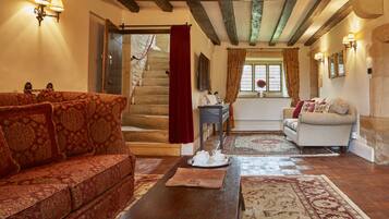A cozy living room with a patterned sofa, a wooden coffee table, and a staircase leading to a bedroom.