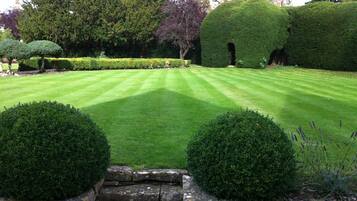 A well-maintained garden with neatly trimmed hedges and a stone wall.