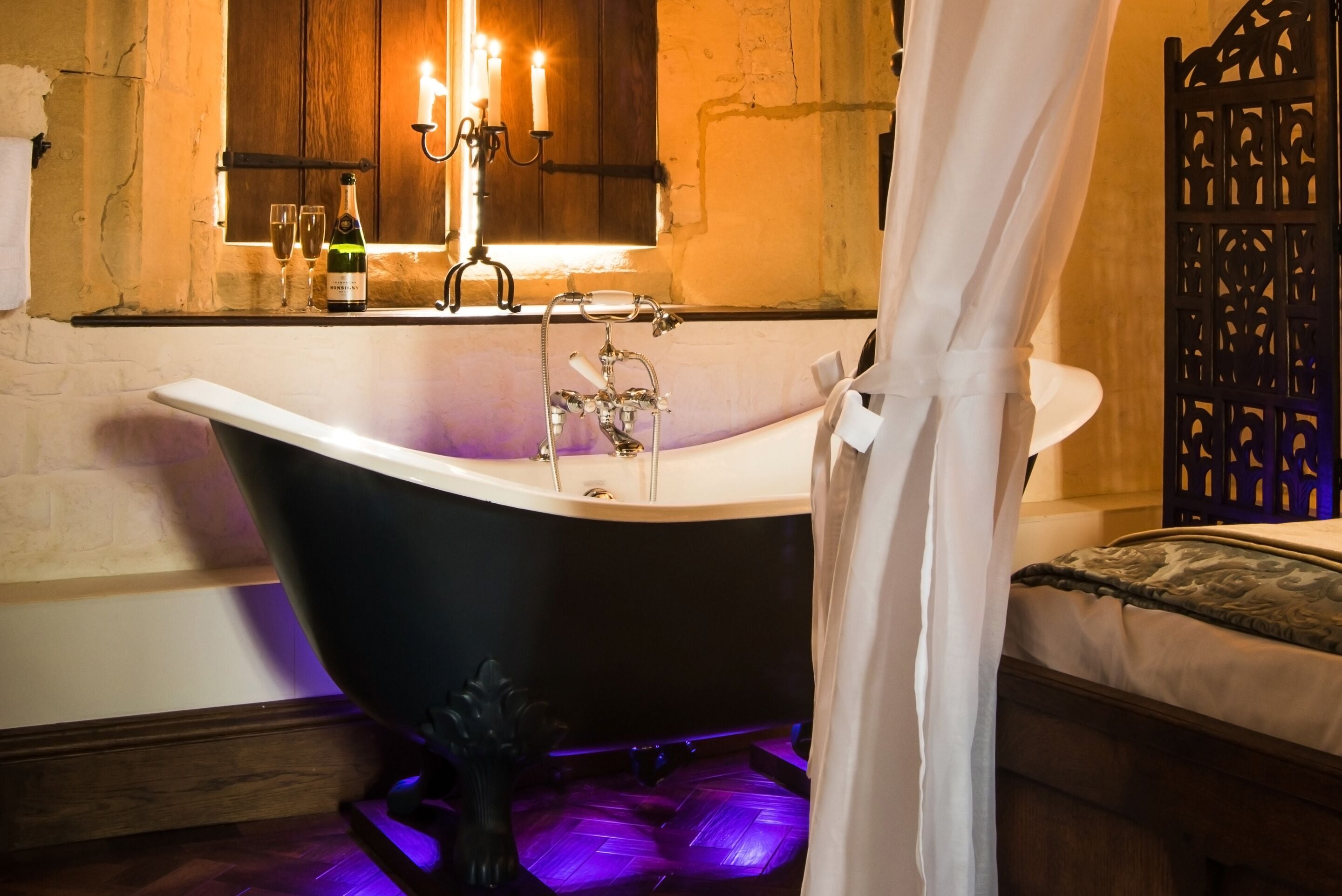 A bathroom with a freestanding bathtub, a window with candles, and a decorative plant.