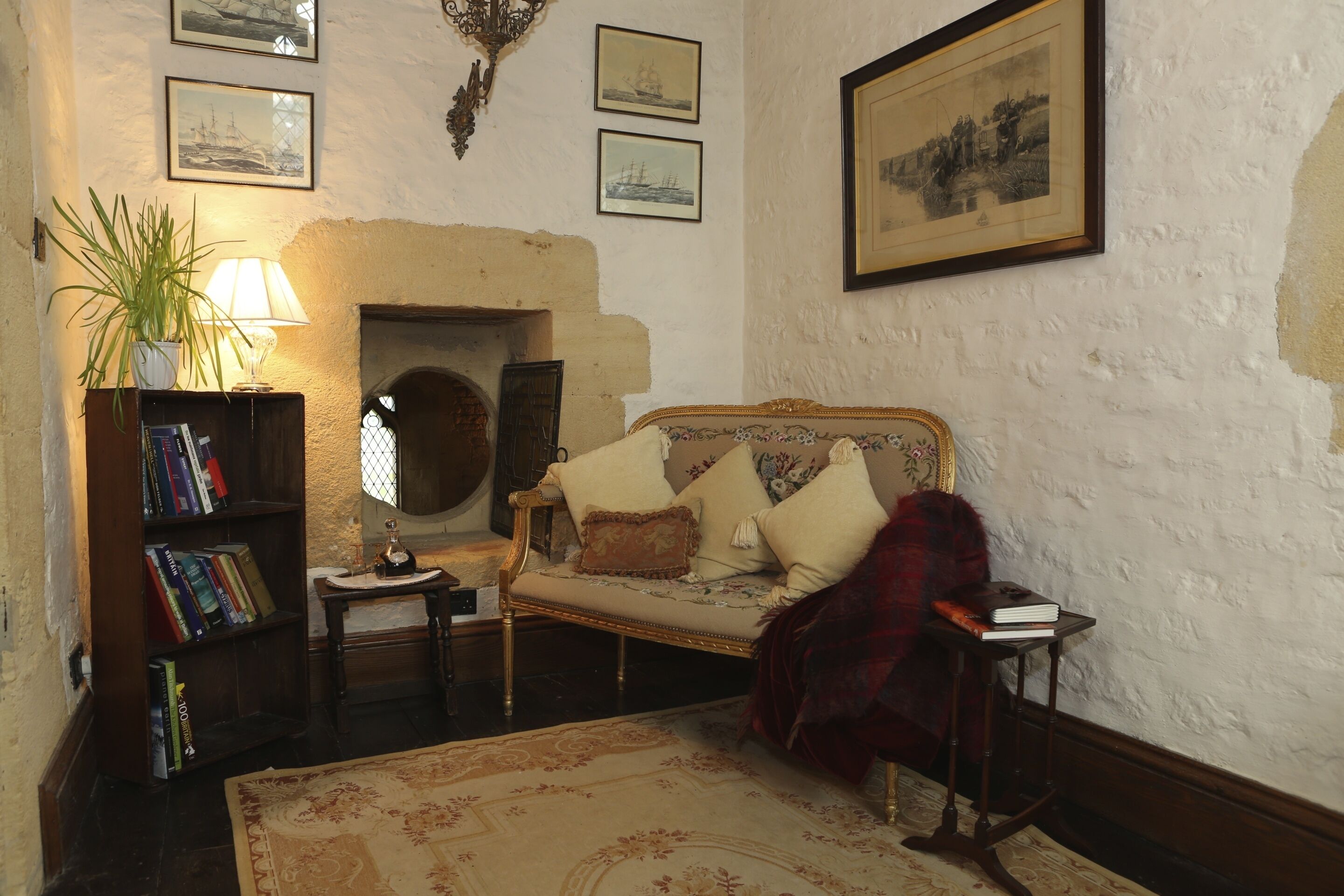 A cozy living room with a fireplace, a sofa, a bookshelf, and a framed picture on the wall.