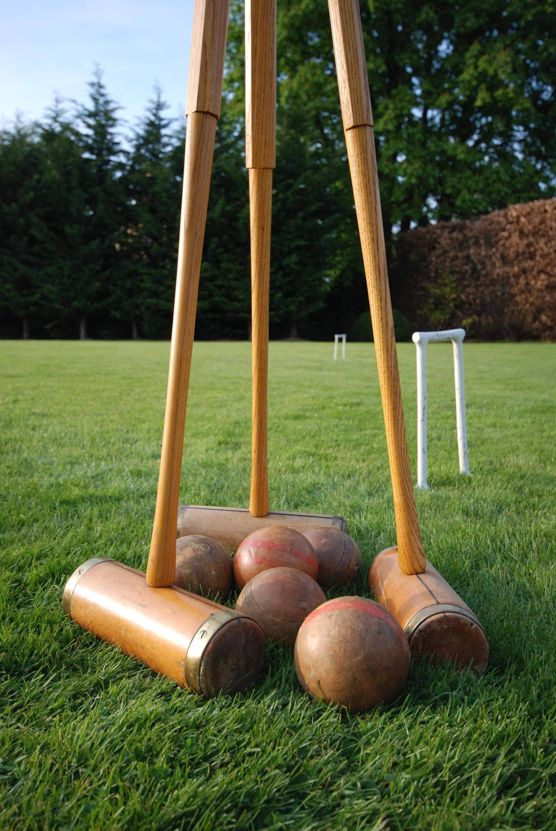 A croquet set on a grassy field with trees in the background.
