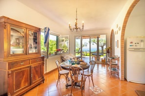 A dining area with a wooden cabinet, a chandelier, and a view of the outdoors.