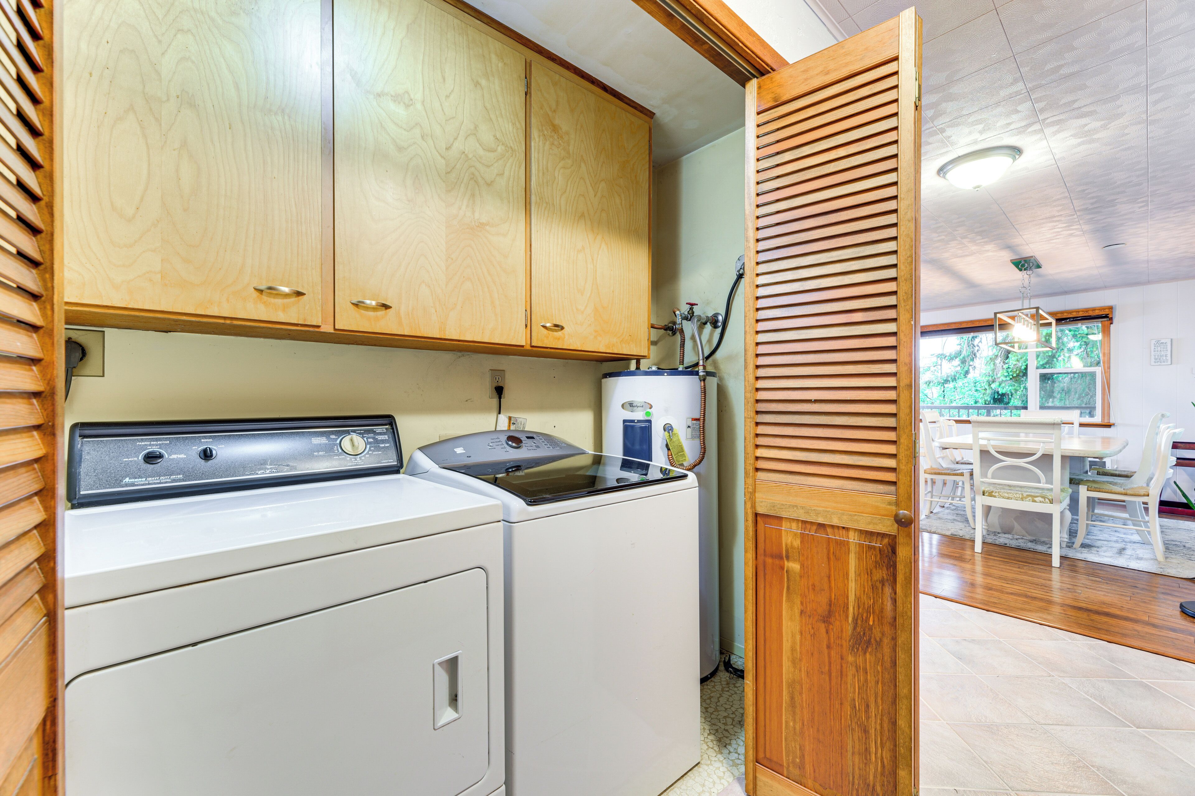 A laundry room with wooden cabinets and a washing machine.