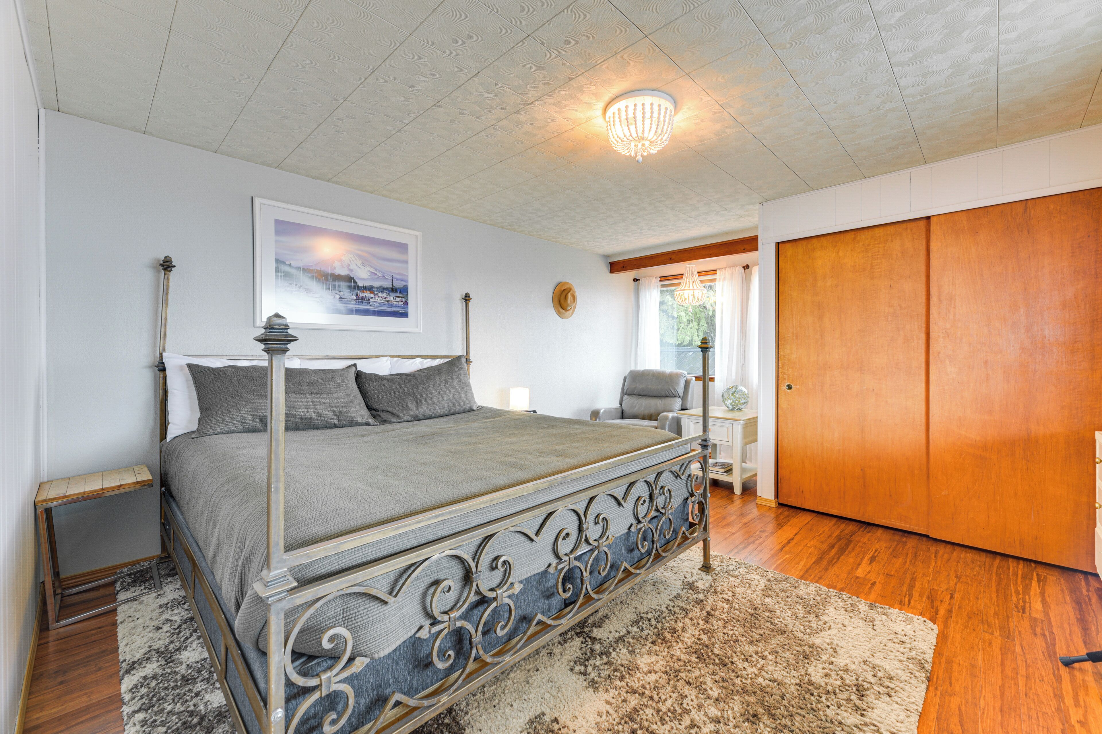 A bedroom with a four-poster bed, a chandelier, a framed picture on the wall, and a wooden wardrobe.