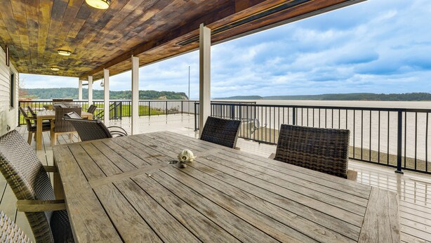 A wooden deck with a table and chairs, overlooking a body of water.