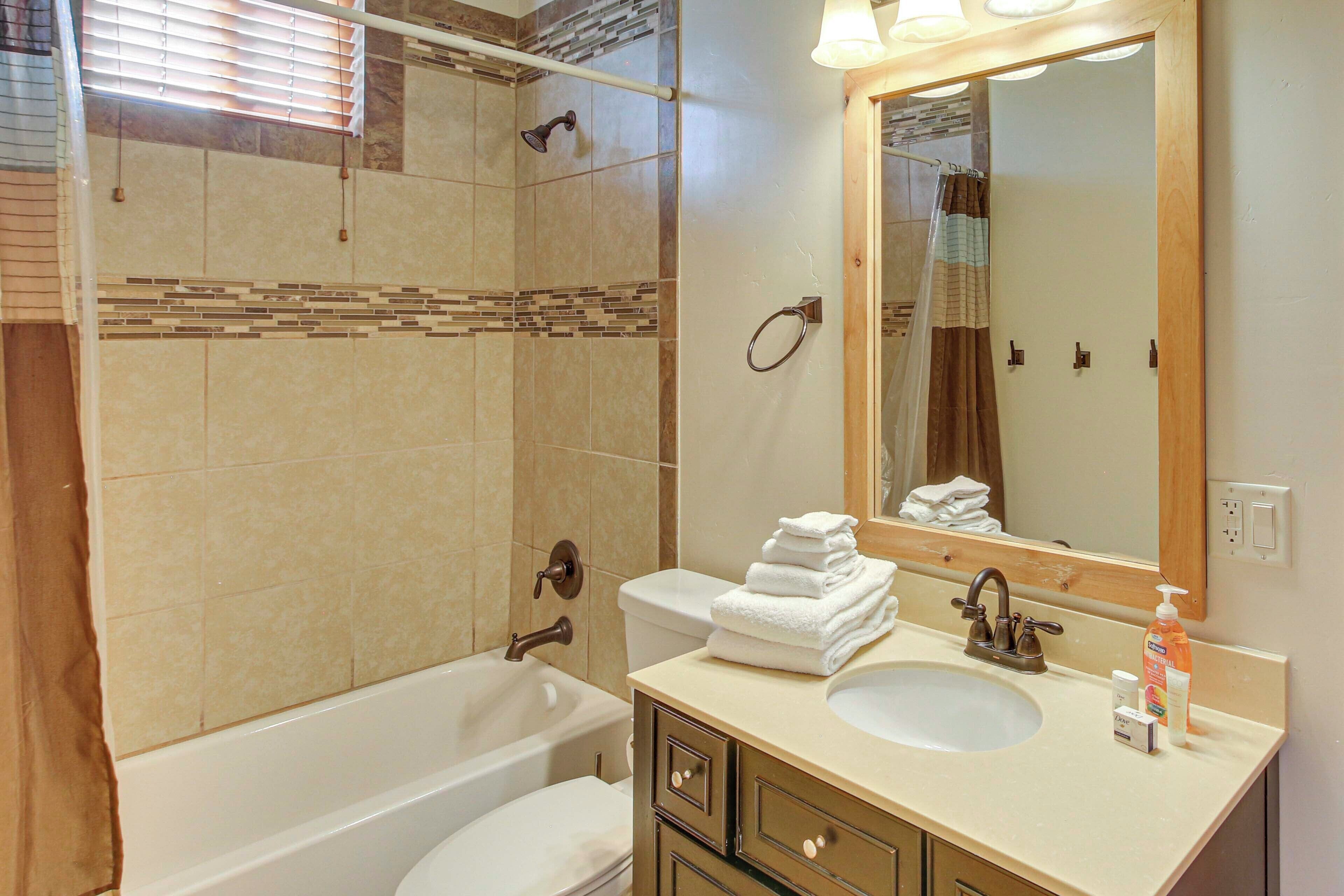 A bathroom with a bathtub, a sink, a mirror, and a shower area.