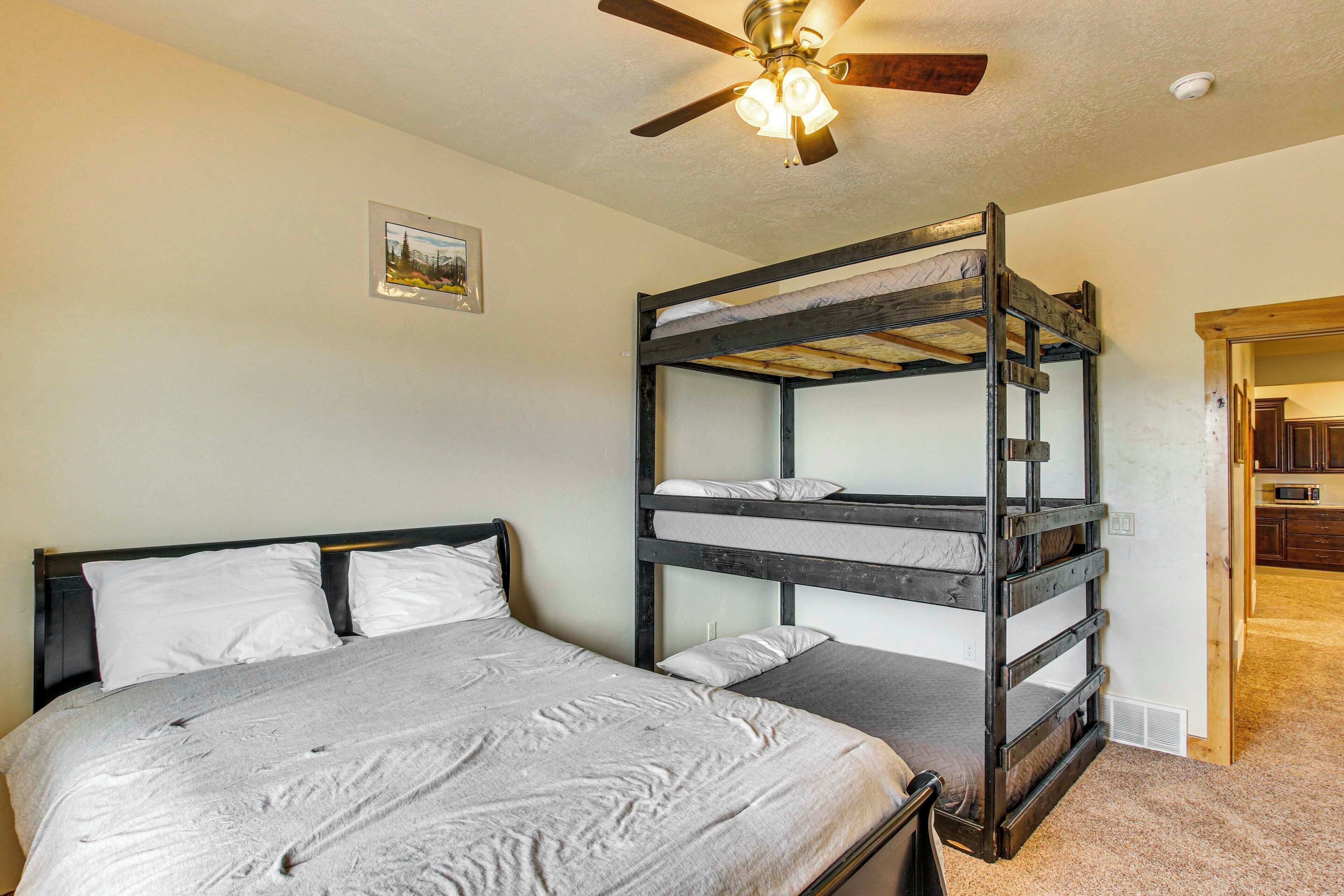 A bunk bed room with a ceiling fan, a single bed, and a small picture on the wall.